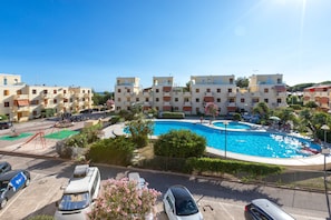 Un hotel con piscina, varios balcones y una zona de estacionamiento.