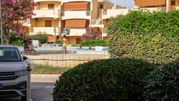 En boligbygning med altaner, en swimmingpool og en parkeret bil.