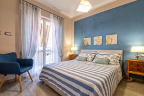 Un dormitorio con una cama, una silla, una mesita de noche y una pared decorada con tres cuadros.