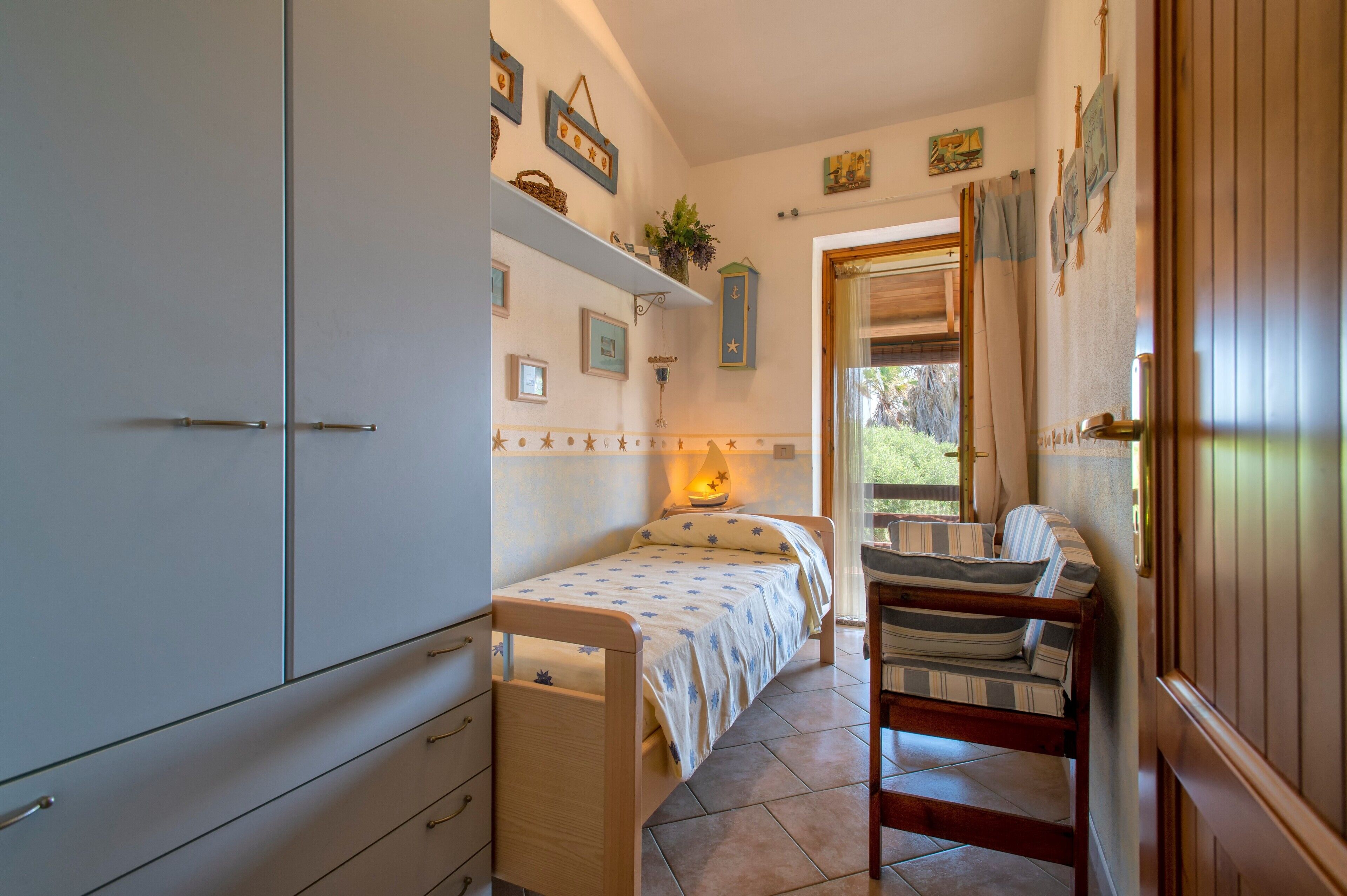 Ein Schlafzimmer mit Bett, Stuhl, Kleiderschrank und einem Fenster mit Vorhängen.