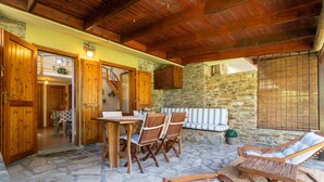 A stone-floored patio with wooden furniture, a dining table, and a staircase leading to an upper level. - Holiday Home 'Stintino La Pelosa' with Private Terrace, Wi-Fi and Air Conditioning (Stintino)
