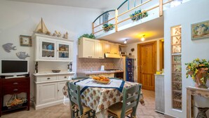A kitchen with a dining table, cabinets, and a TV. - Holiday Home 'Stintino La Pelosa' with Private Terrace, Wi-Fi and Air Conditioning (Stintino)