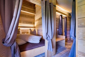 Ein Holzblockhaus-Innenraum mit Bett, Vorhängen und einer Bank.