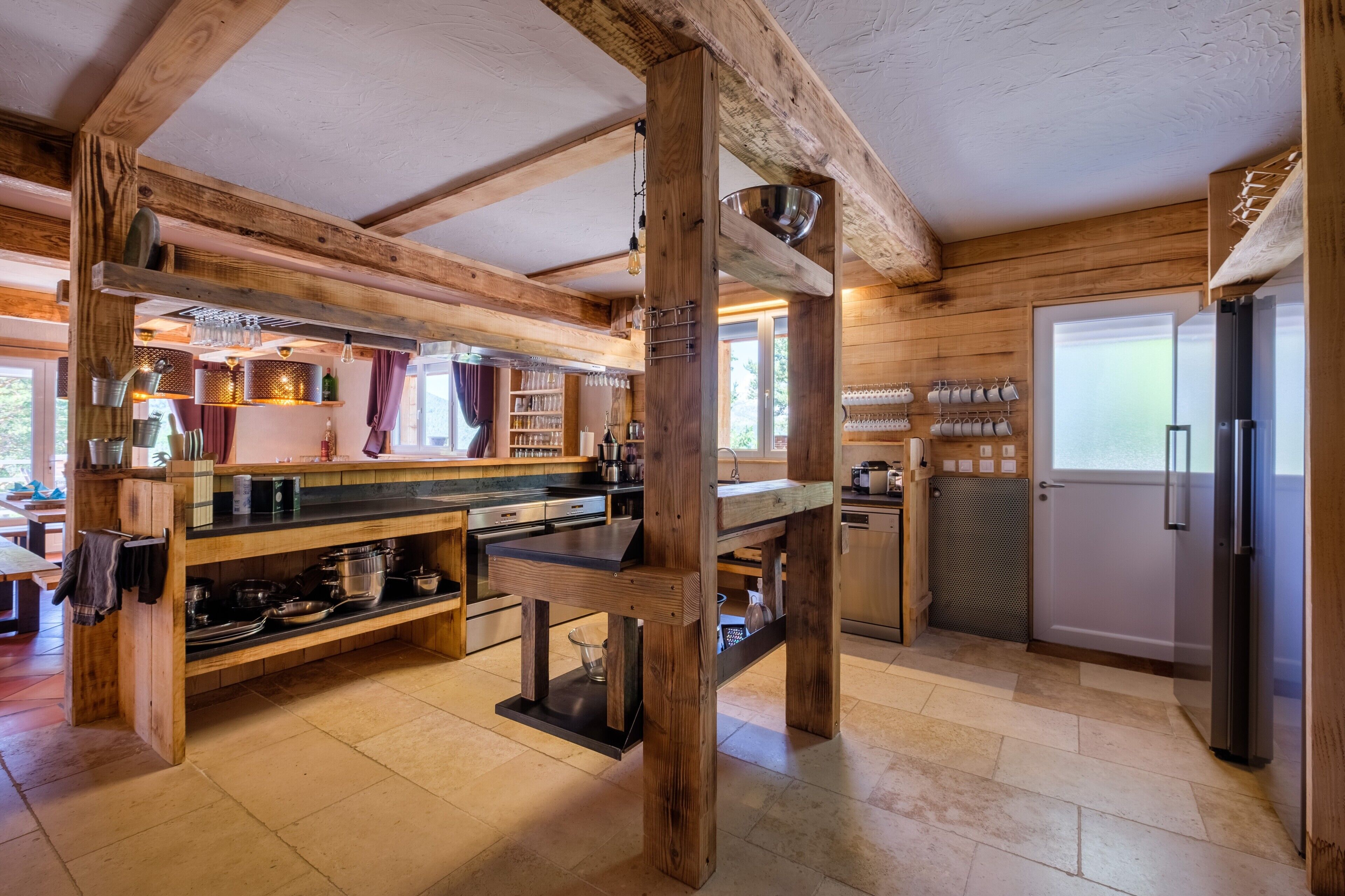 Une cuisine rustique avec des poutres en bois, un îlot central et un réfrigérateur.