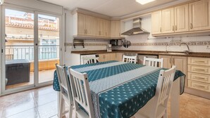Una cocina con comedor, un cerramiento de vidrio corredero y vista a un edificio.