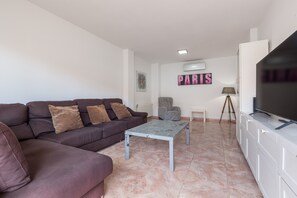 A living room with a sofa, a coffee table, a TV, a tripod, and a wall sign.