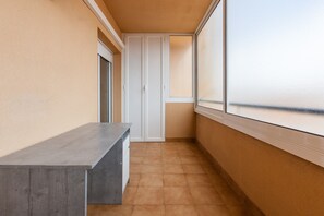 Un couloir étroit avec un banc, une porte et une fenêtre donnant sur un paysage.