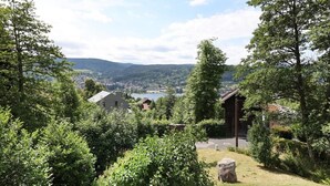 Une vue d’un paysage rural, avec un bâtiment entouré d’arbres et une ville située au loin.