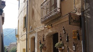 Un carrer estret amb paviment de pedra, un edifici amb el rètol 'Caffinetti' i amples penjolls de botelles de vi.