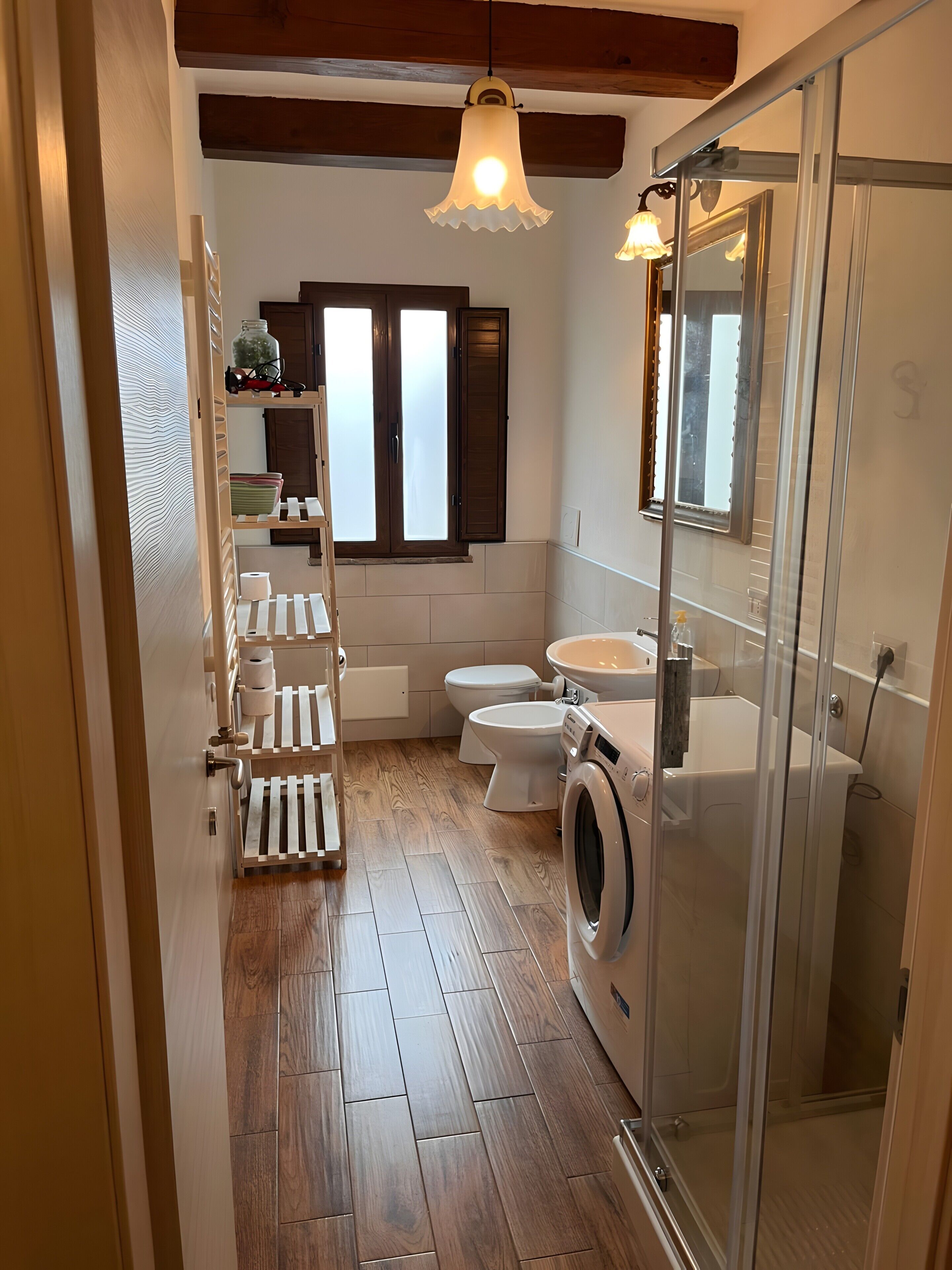 A bathroom with a washing machine, toilet, and a glass shower enclosure.