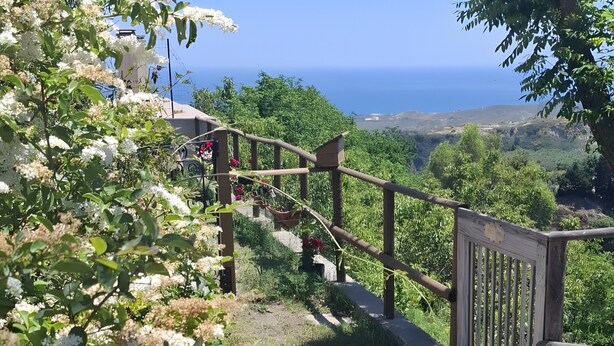 Un camí empedrat que condueix a una porta de fusta amb vista al mar.