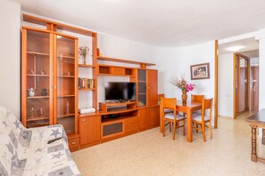 Un soggiorno con televisione, mobili in legno, un divano e un'area pranzo.