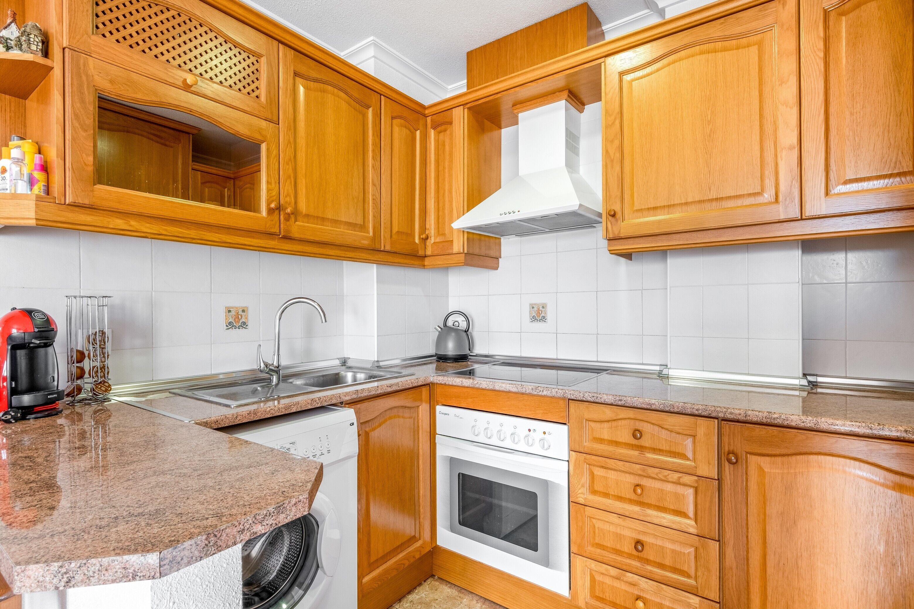 A kitchen with wooden cabinets, a dishwasher, an oven, and a coffee maker.