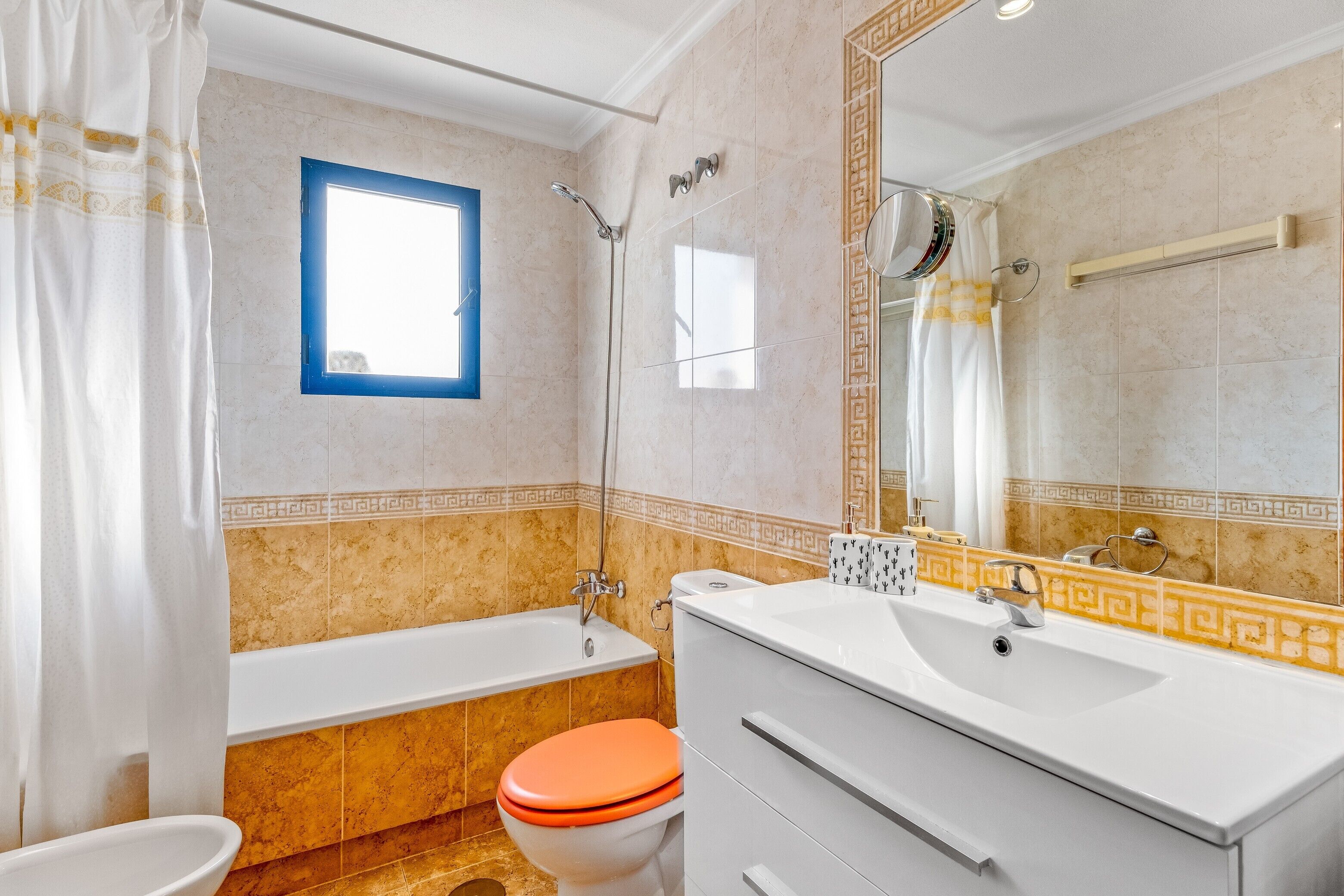 Un baño con bañera, inodoro, lavabo y un espejo grande.