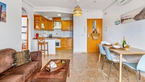Uma sala de estar moderna com sofá, mesa de centro e área de jantar com cadeiras e mesa posta para refeição.