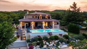 A two-story house with a swimming pool, outdoor seating, and a landscaped garden.