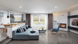 A modern living room with a sofa, a coffee table, a fireplace, and a television.