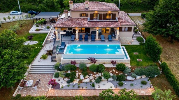 A two-story house with a swimming pool, outdoor seating, and a well-maintained garden.