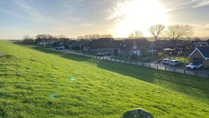 Un paysage rural avec des maisons, un champ d’herbe et des voitures garées.