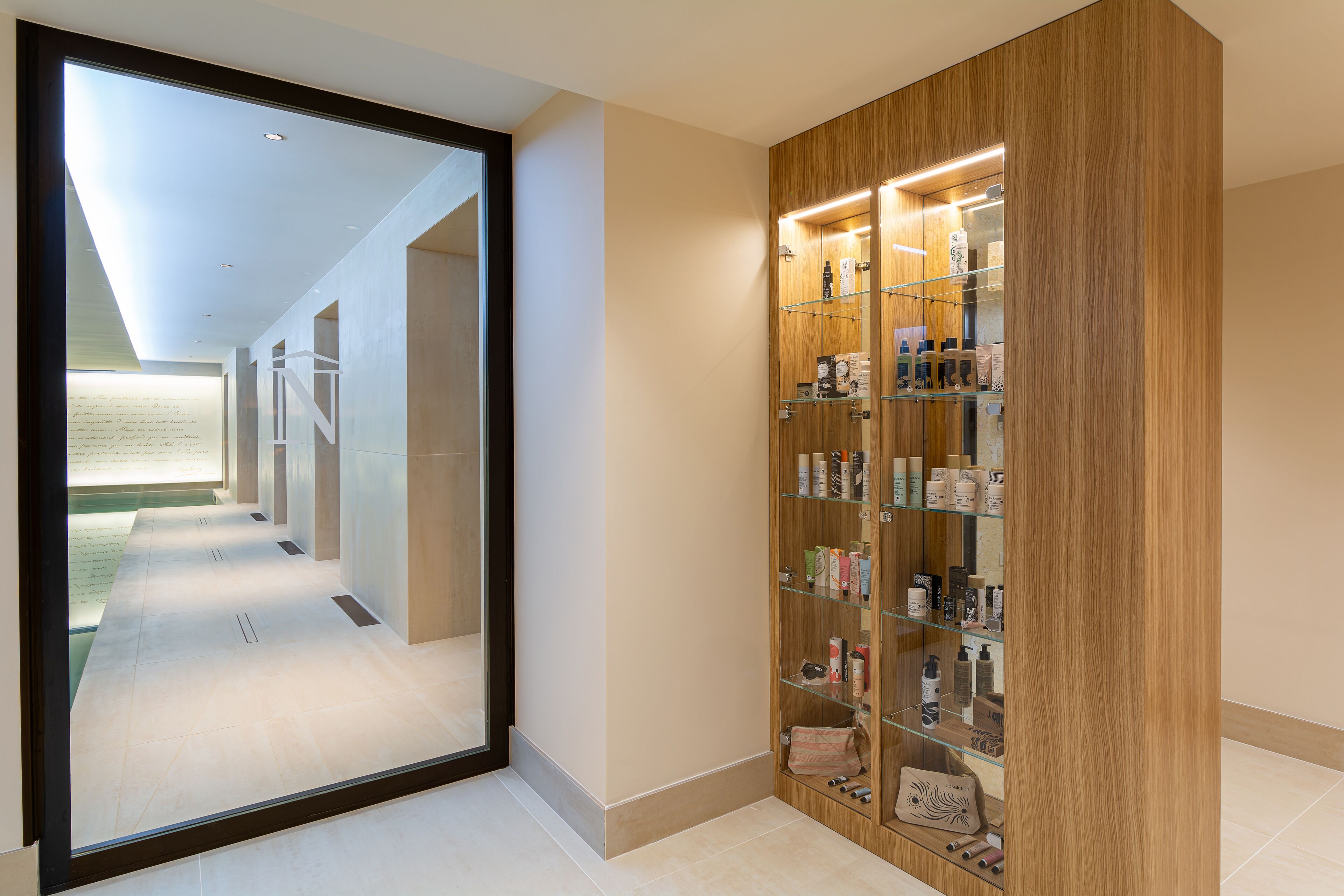 A hallway with a wooden vanity and a glass display cabinet filled with toiletries.