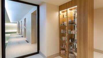 A hallway with a wooden vanity and a glass display cabinet filled with toiletries.
