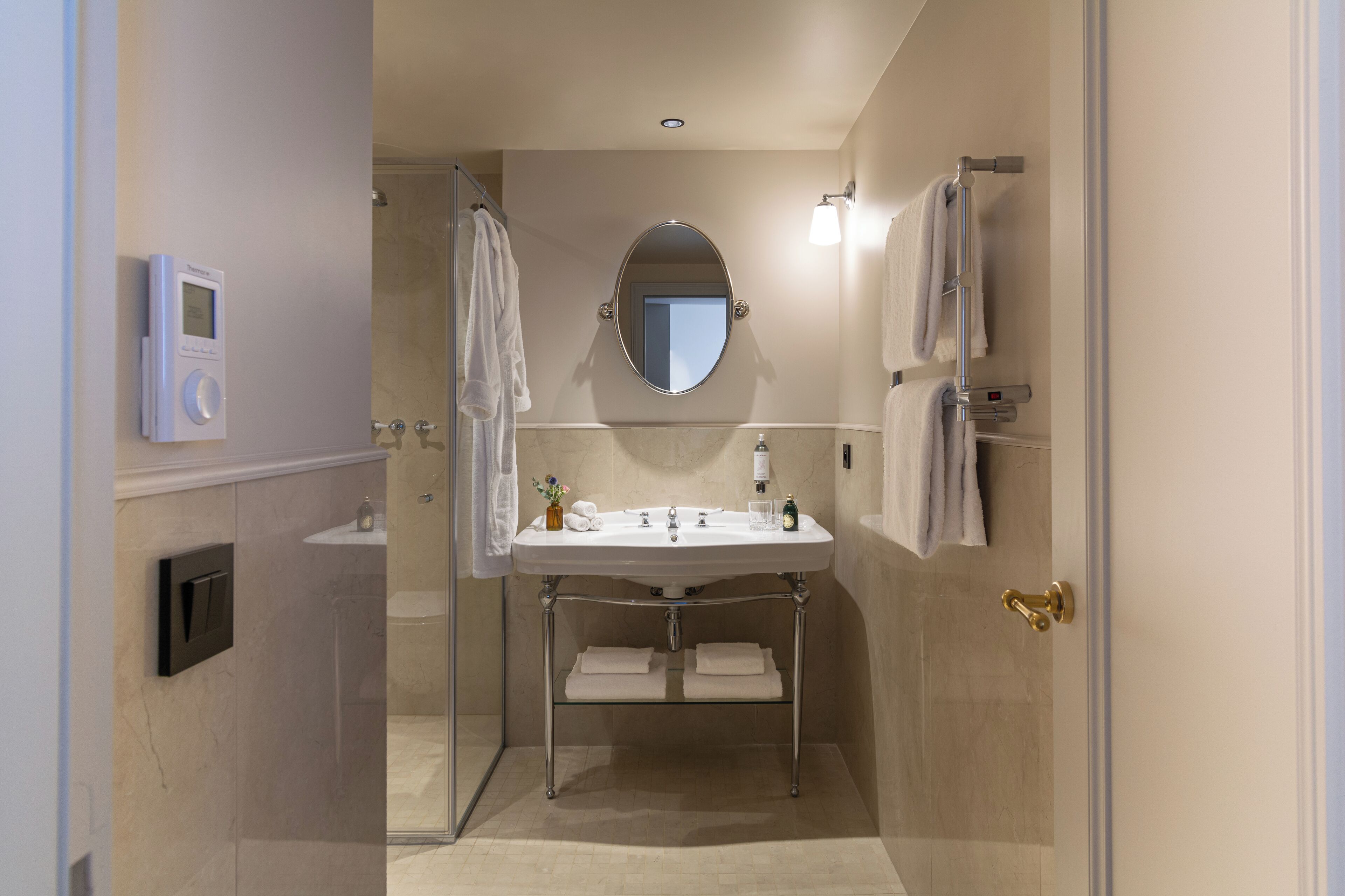 Une salle de bain moderne avec une douche à parois de verre, un meuble-lavabo avec un miroir et un porte-serviettes.