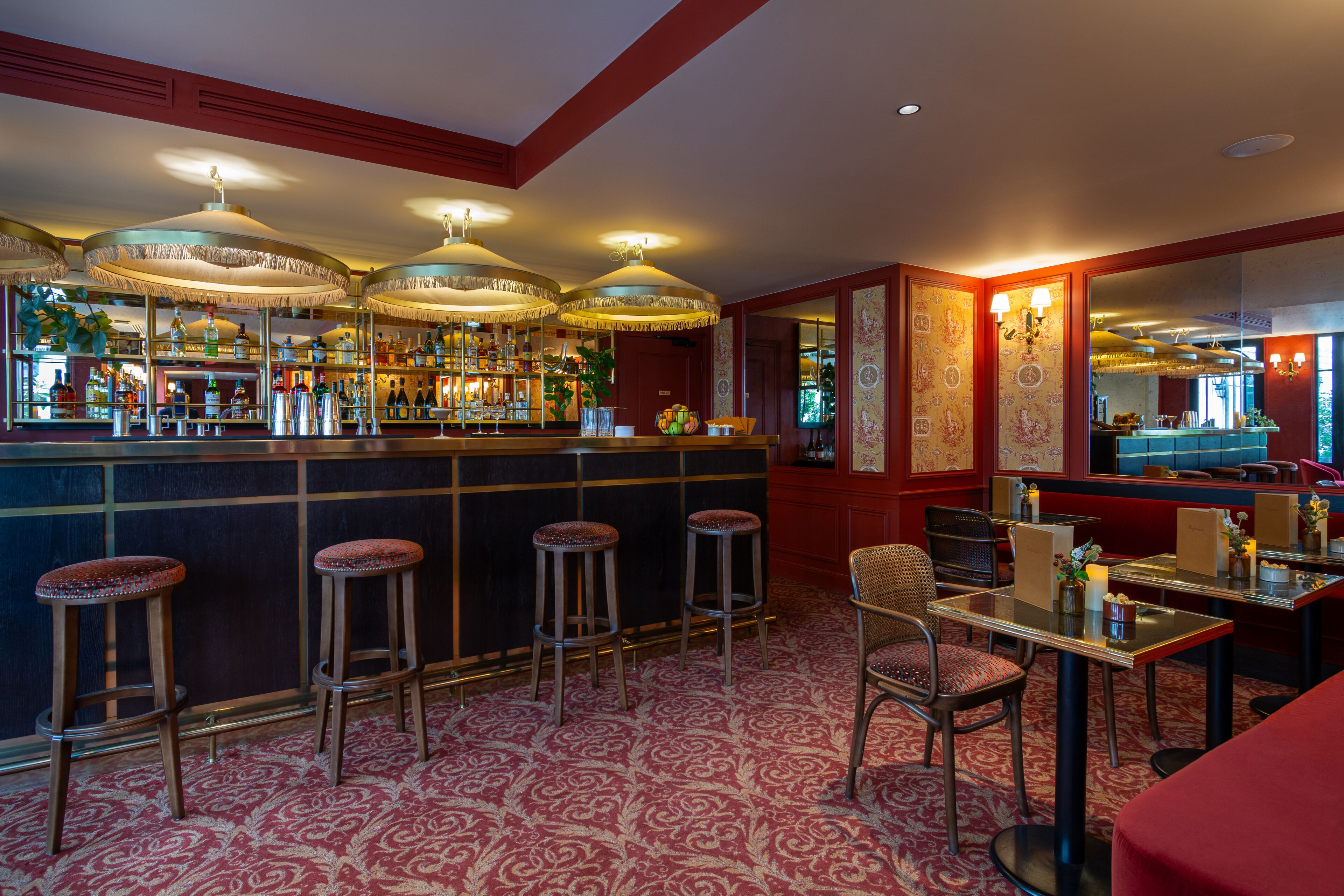 A bar area with stools, a counter with bottles, and a patterned carpet.