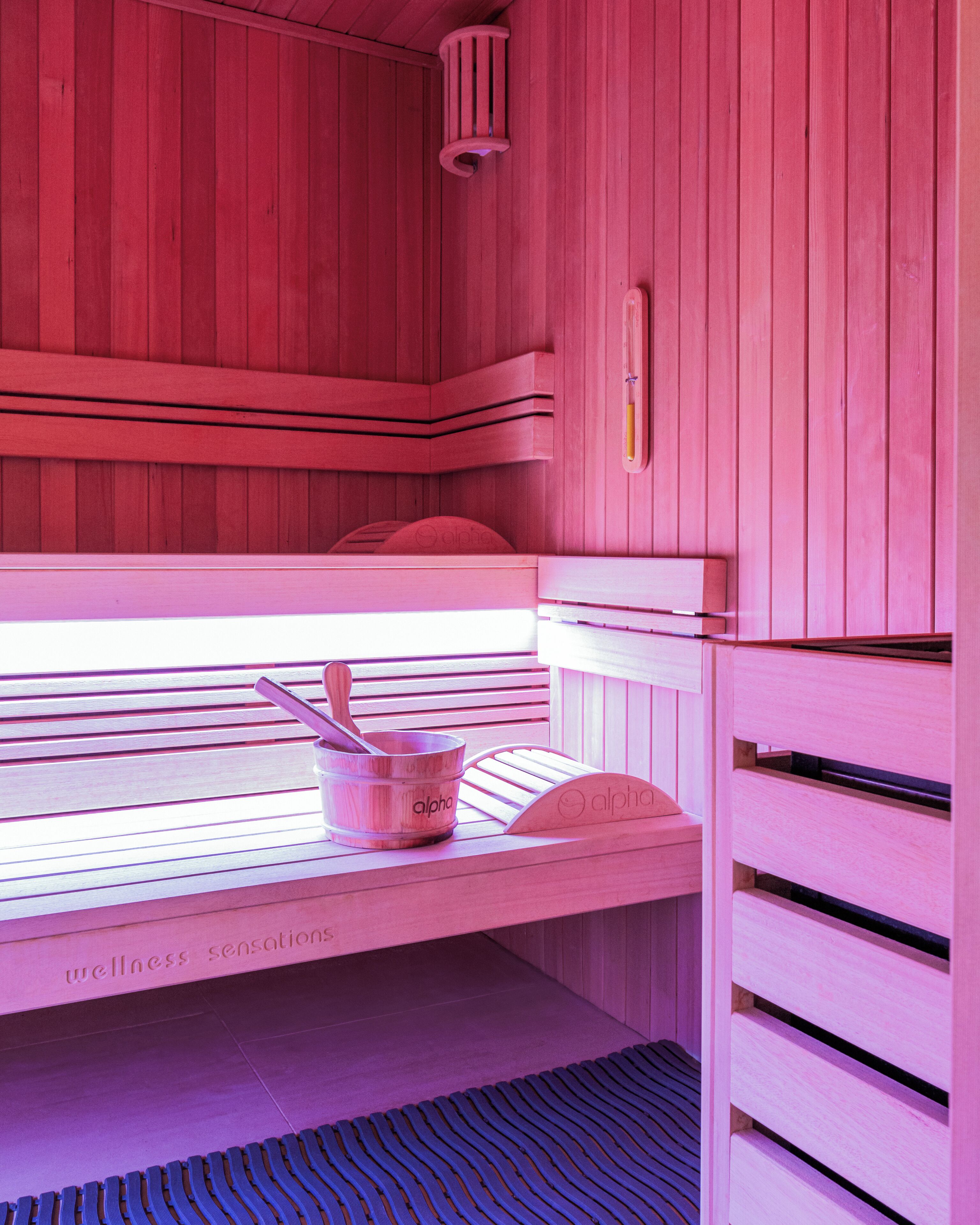 A sauna with wooden benches, a bench heater, and a towel rack.