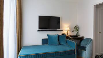 A hotel room with a bed, a TV mounted on the wall, a bedside table with a lamp, and a chair.