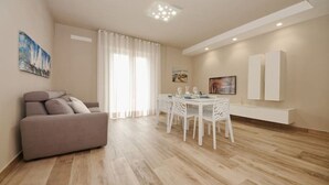 A modern living room with a sofa, dining table, and chairs.