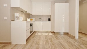 A modern kitchen with white cabinetry, a built-in oven, and a microwave.