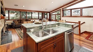 A spacious kitchen with a large island, wooden cabinetry, and a view of the outdoors.
