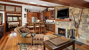 A spacious living room with a fireplace, wooden furniture, and a stone wall.