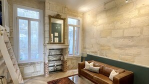 A spacious room with a herringbone floor, a brown leather sofa, a large mirror, and a fireplace. - Charming Artistic and Historic Chartrons Flat with Private Patio
 (Bordeaux)
