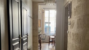 A hallway with wooden flooring, a chandelier, and a view into a dining area with a table and chairs. - Charming Artistic and Historic Chartrons Flat with Private Patio
 (Bordeaux)