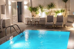 Un'area piscina con una piscina blu cristallina, lettini e piante in vaso.