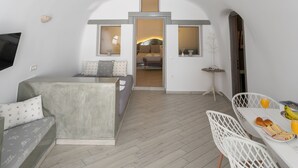 Un espace de vie moderne et compact comprenant un coin repas, un canapé et un téléviseur fixé au mur.