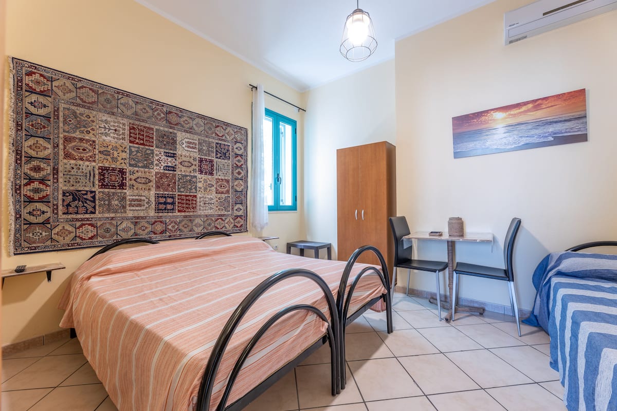 Un dormitorio con una cama, un escritorio, una silla, un armario y un tapete grande.
