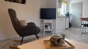 Un soggiorno moderno con un divano, una TV a schermo piatto, un acquario in vetro su base in legno e un'area pranzo con tavolo e sedie.