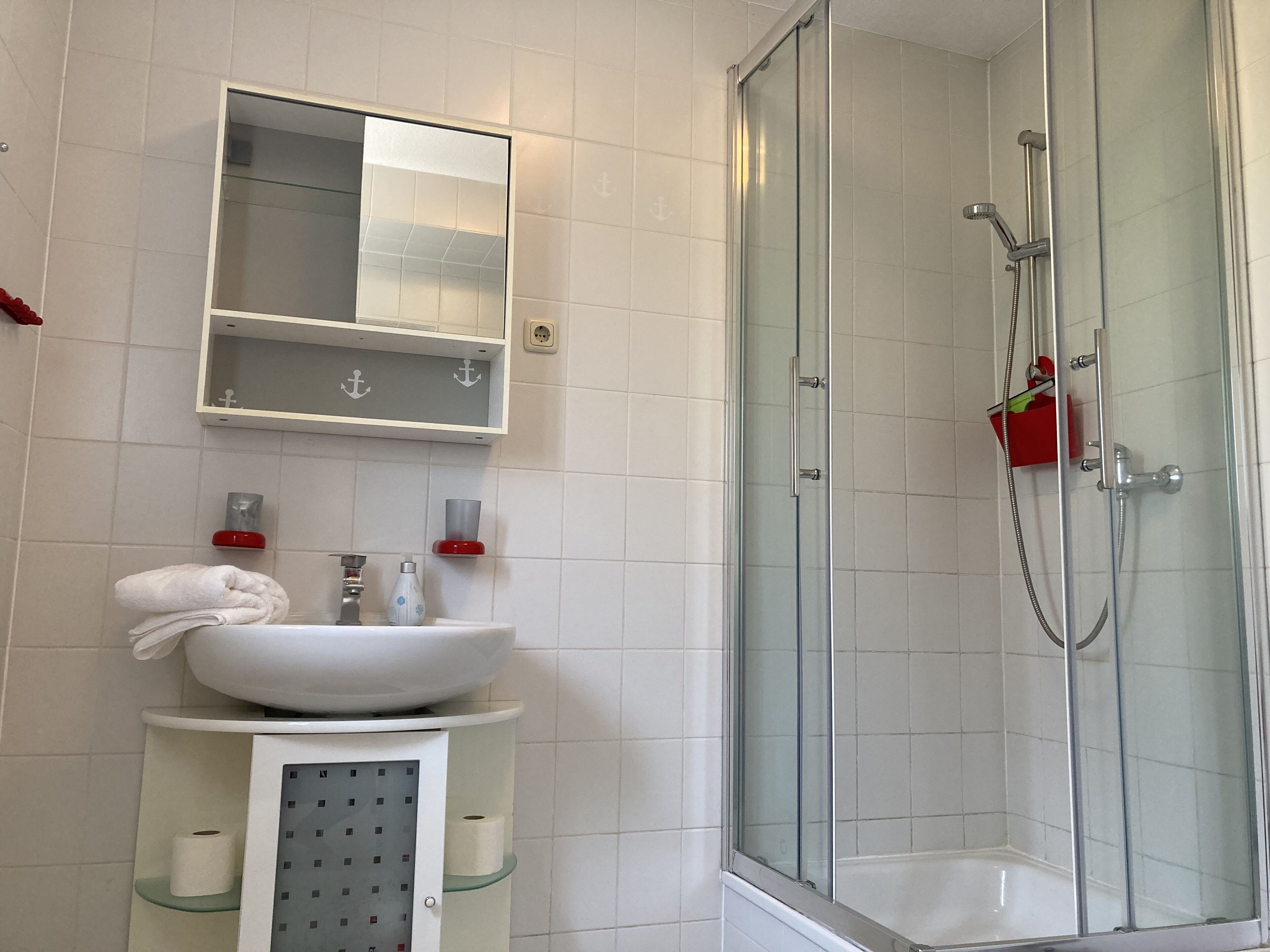 A bathroom with a glass-enclosed shower, a white sink, and a mirror above it.