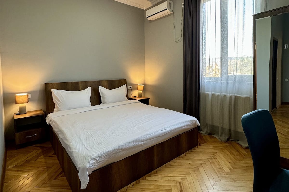 Une chambre d’hôtel avec un grand lit, un plancher en bois, un bureau et une chaise.