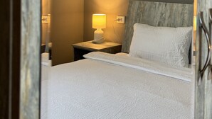 Une chambre d’hôtel avec un lit, une table de chevet avec une lampe et une tête de lit en bois.