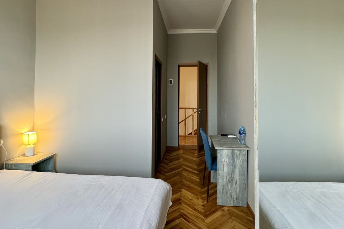 Une chambre d’hôtel avec deux lits, un bureau, une chaise et une lampe.