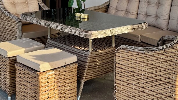 Un espace de détente aménagé avec des meubles en osier, une table à plateau en verre, des fauteuils rembourrés et un canapé.