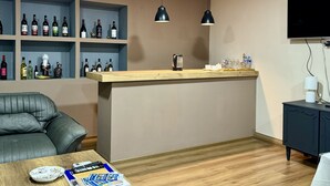 Un salon moderne avec une table basse en bois, un canapé en cuir, un meuble à vin intégré et un téléviseur à écran plat fixé au mur.