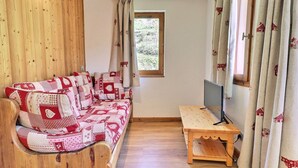 Une pièce chaleureuse avec un canapé en bois, une petite table en bois et un téléviseur.