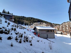 A snow-covered ski slope with a small lodge and a mountain town in the background. - Comfortable 2 Rooms, Ski-in, Near Shops (La Tania)
