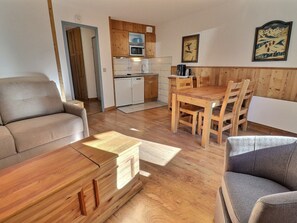 Um espaço de estar compacto com cozinha compacta, mobiliário de madeira e sofá.