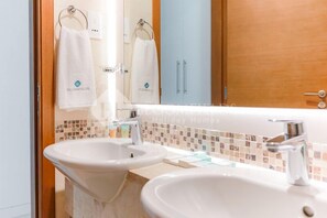 Ein Badezimmer mit zwei Waschbecken, einem Spiegel und einer Holztür.