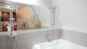 A modern bathroom with a large bathtub, a shower with a handheld showerhead, and a mirror above the sink.